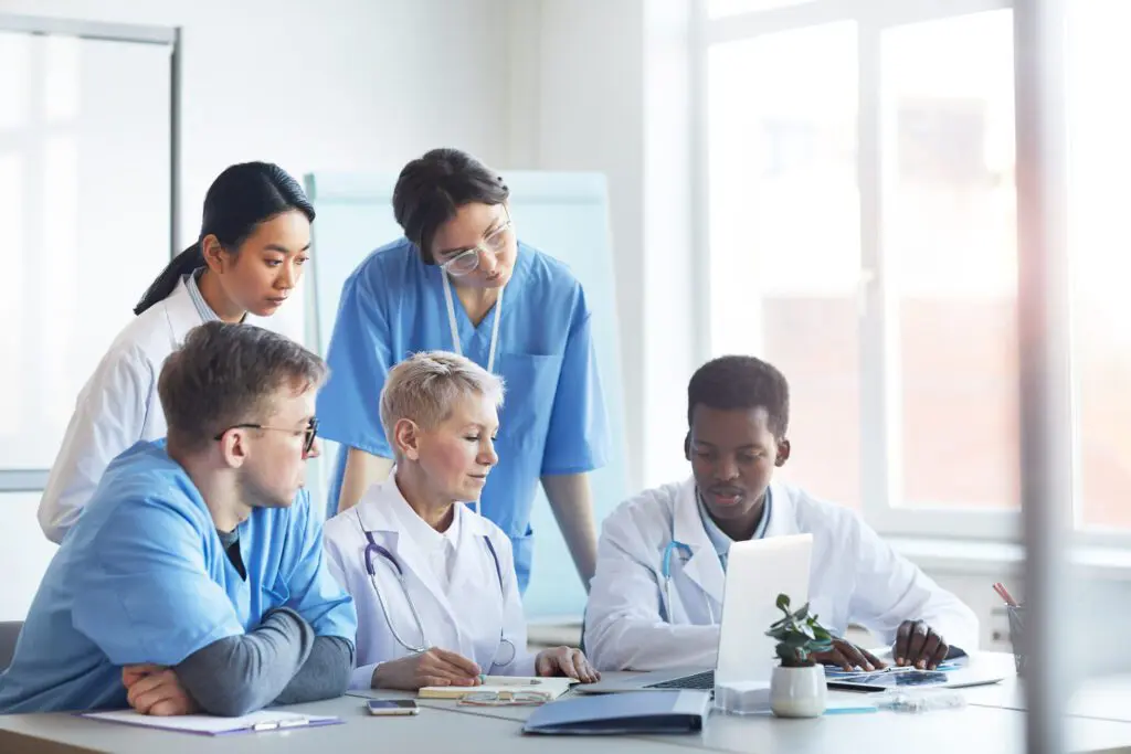 A group of veterinarians and techs looking at a laptop in a conference room.