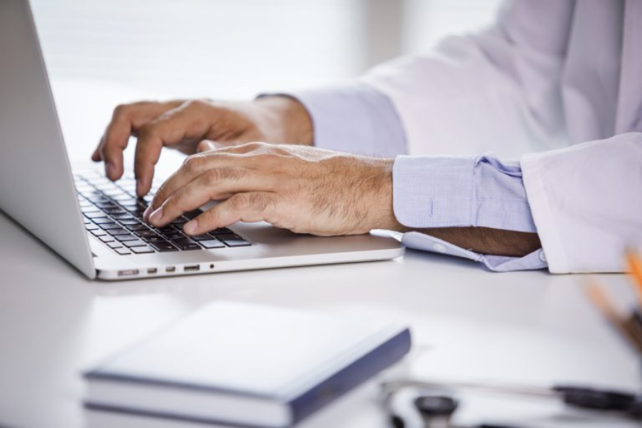 Mans hands in view typing on laptop keyboard